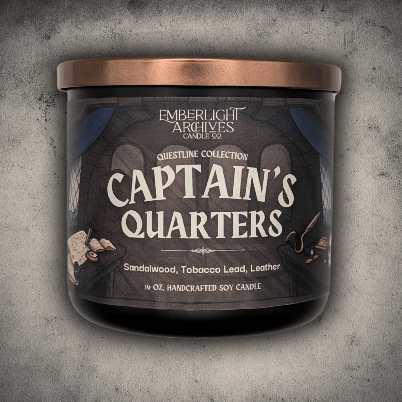 Emberlight Archives Captain's Quarters candle in a 16oz black glass jar with illustrated pirate ship label against a gray stone background, Tobacco and Sandalwood scent.